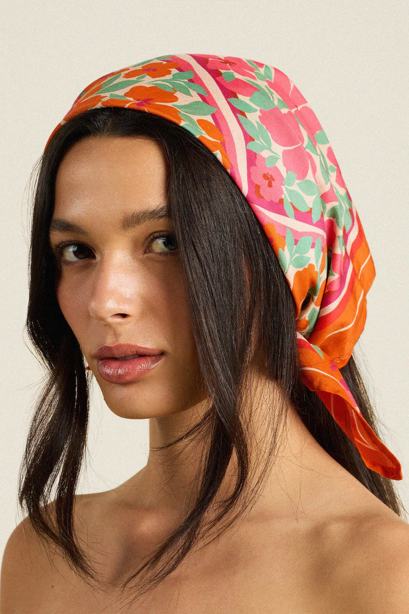 Woman wearing a colorful headscarf with a neutral background