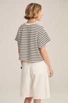 Person wearing a striped shirt and white shorts on a plain background