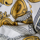 Close-up of a patterned fabric with yellow and black designs on a white background