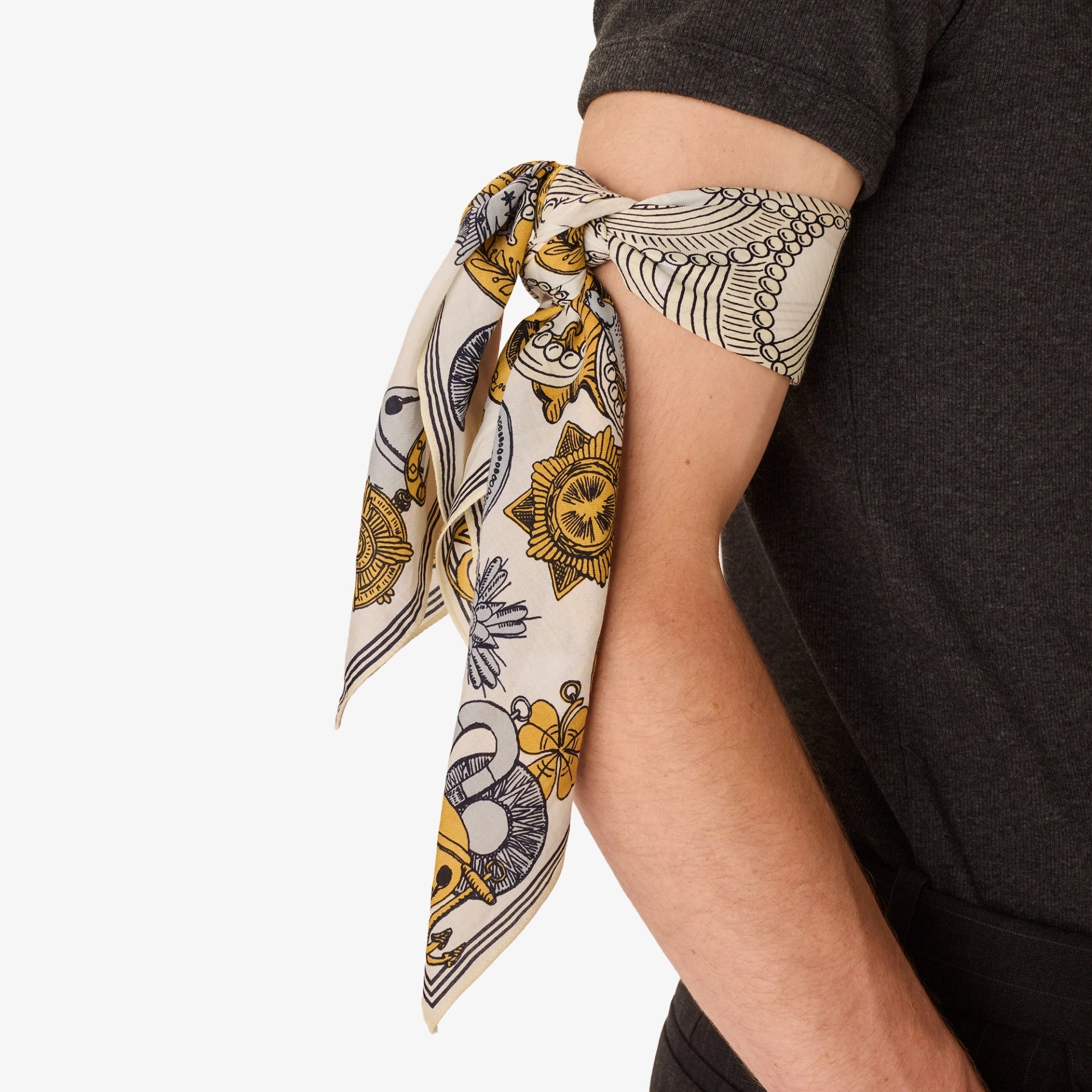 Decorative scarf with yellow and black patterns draped over a person's arm on a white background