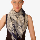 Woman wearing a patterned scarf on a plain background