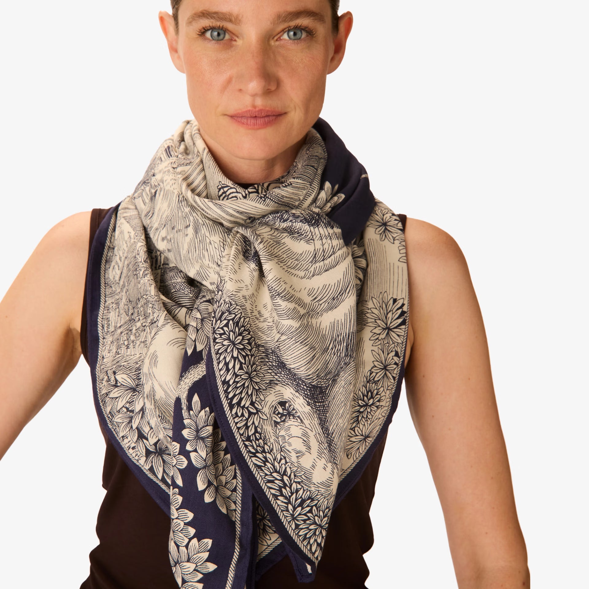 Woman wearing a patterned scarf on a plain background