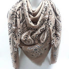 Beige scarf with black paisley pattern draped over a mannequin on a white background