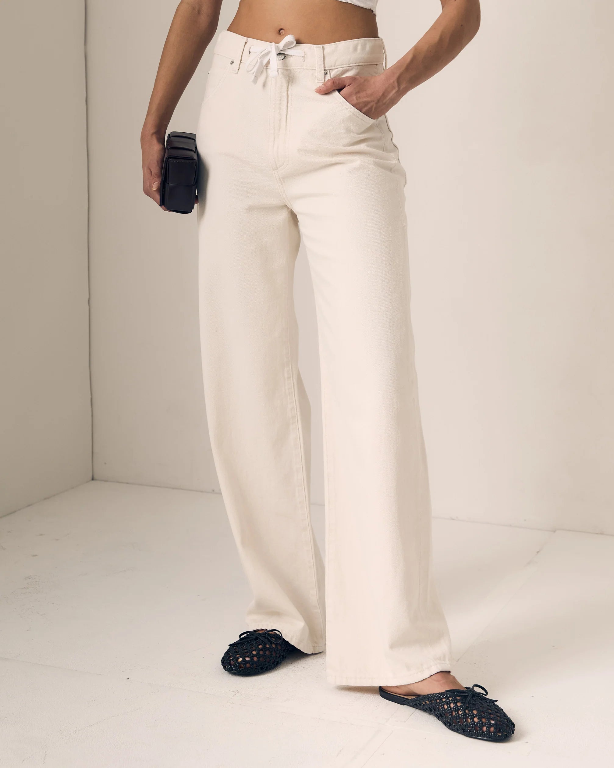 Person wearing white pants with a plain background