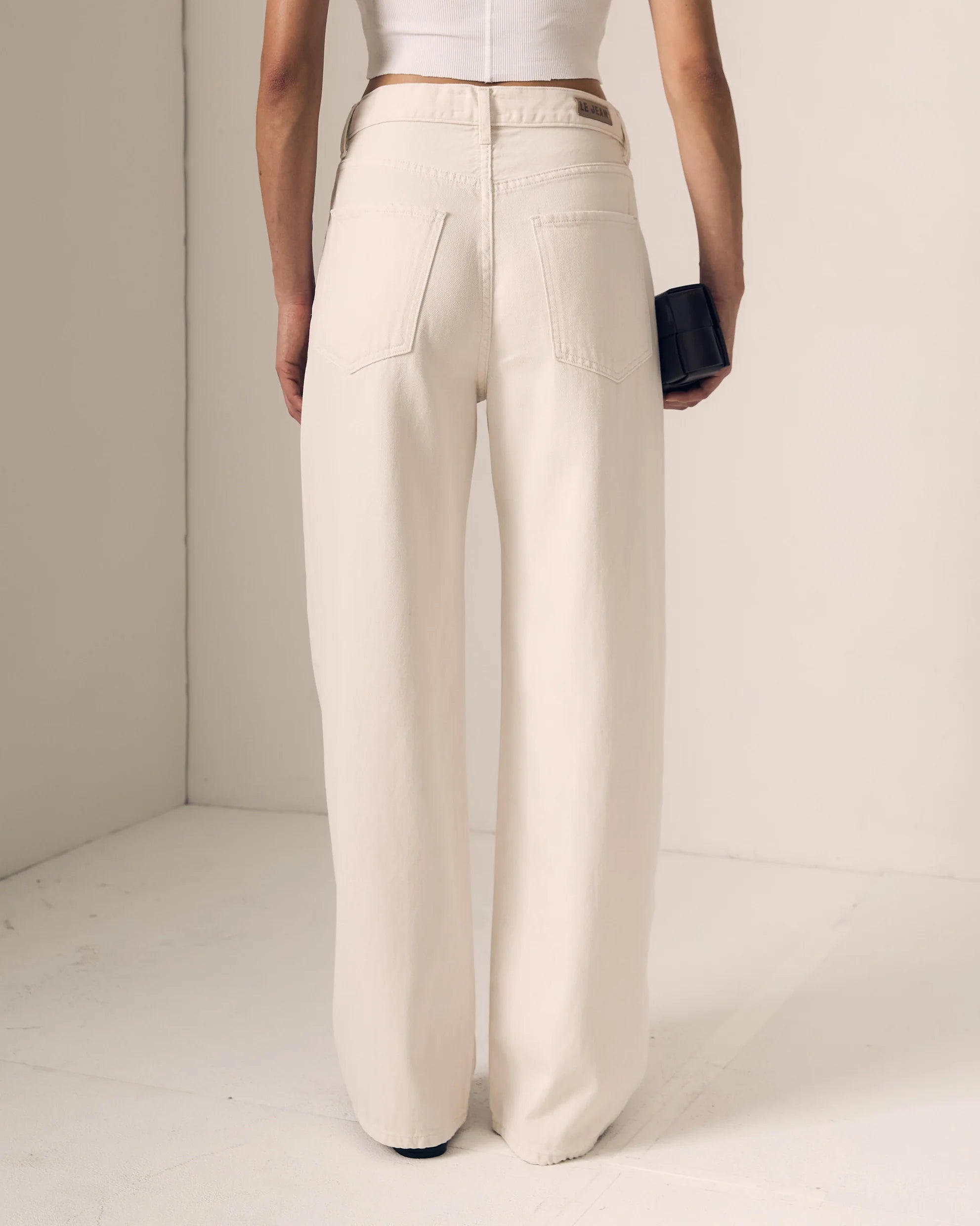 Person wearing white pants and a white top against a plain background