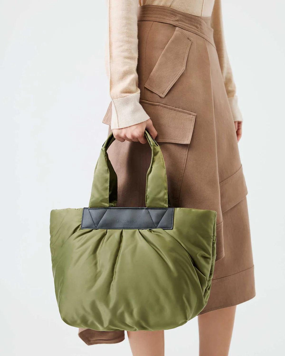 Person holding a green bag with a neutral background