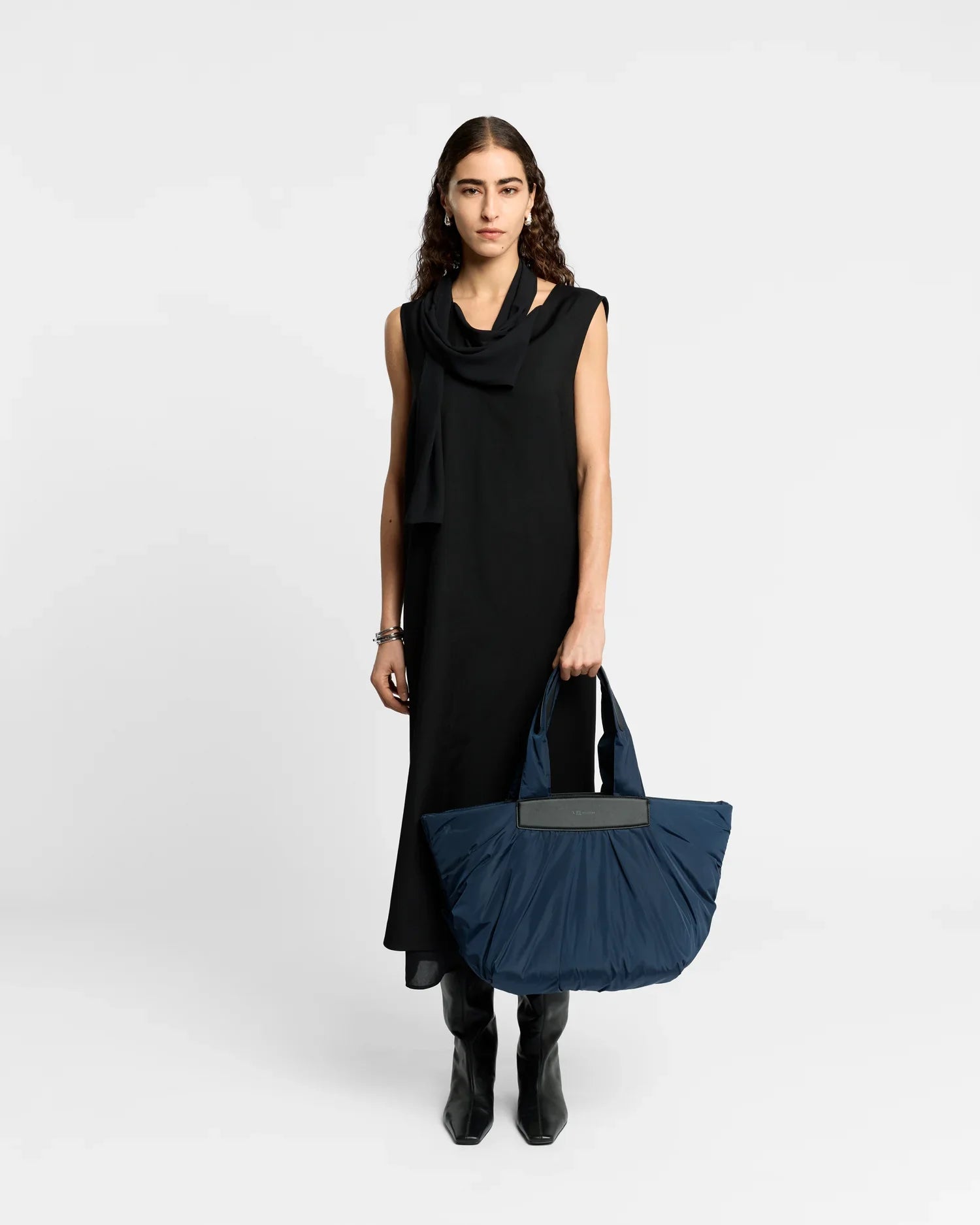 Woman holding a navy blue bag against a white background
