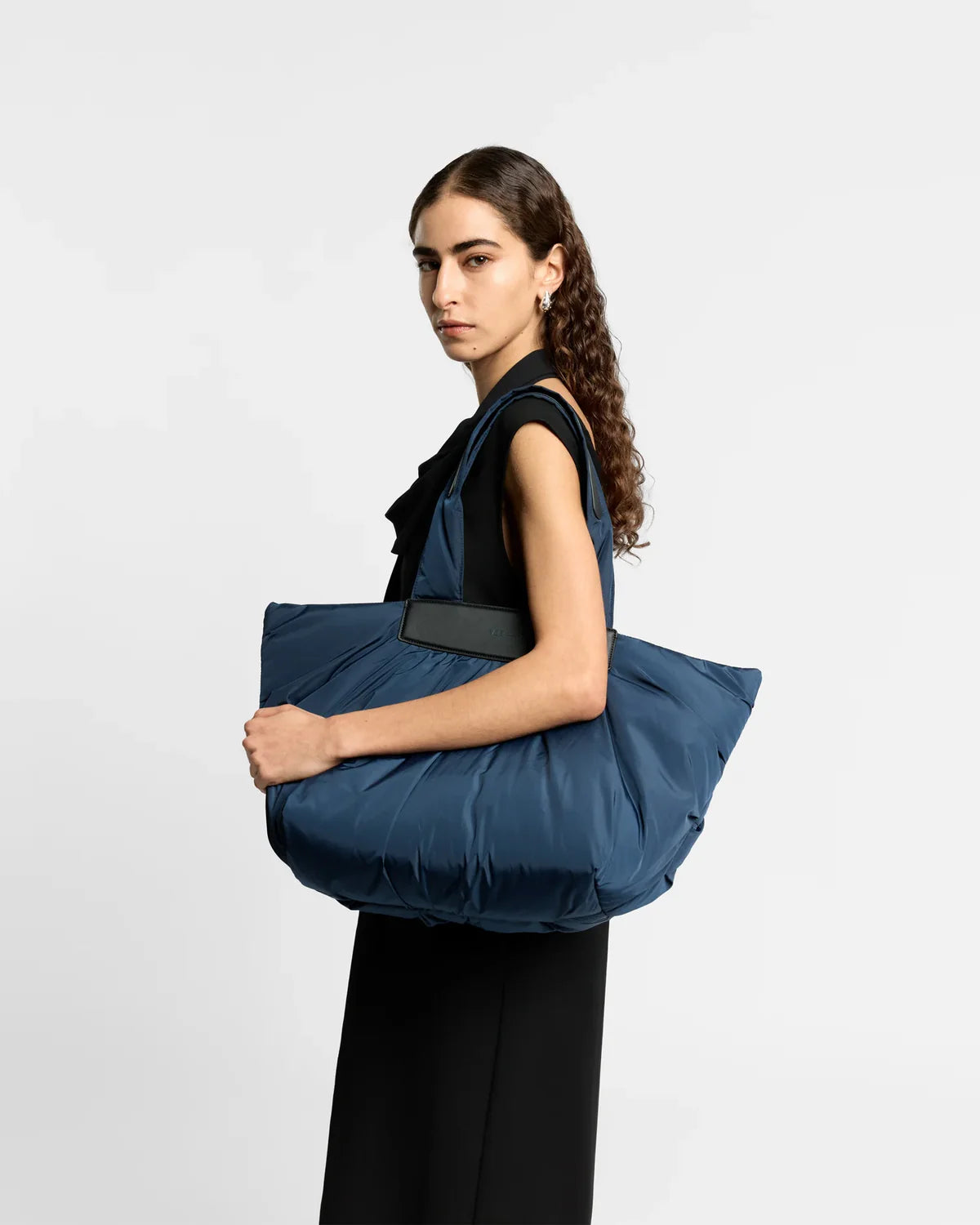 Woman holding a blue tote bag against a white background