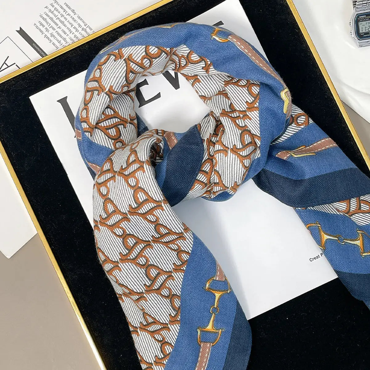 Patterned scarf on a magazine with a visible brand logo