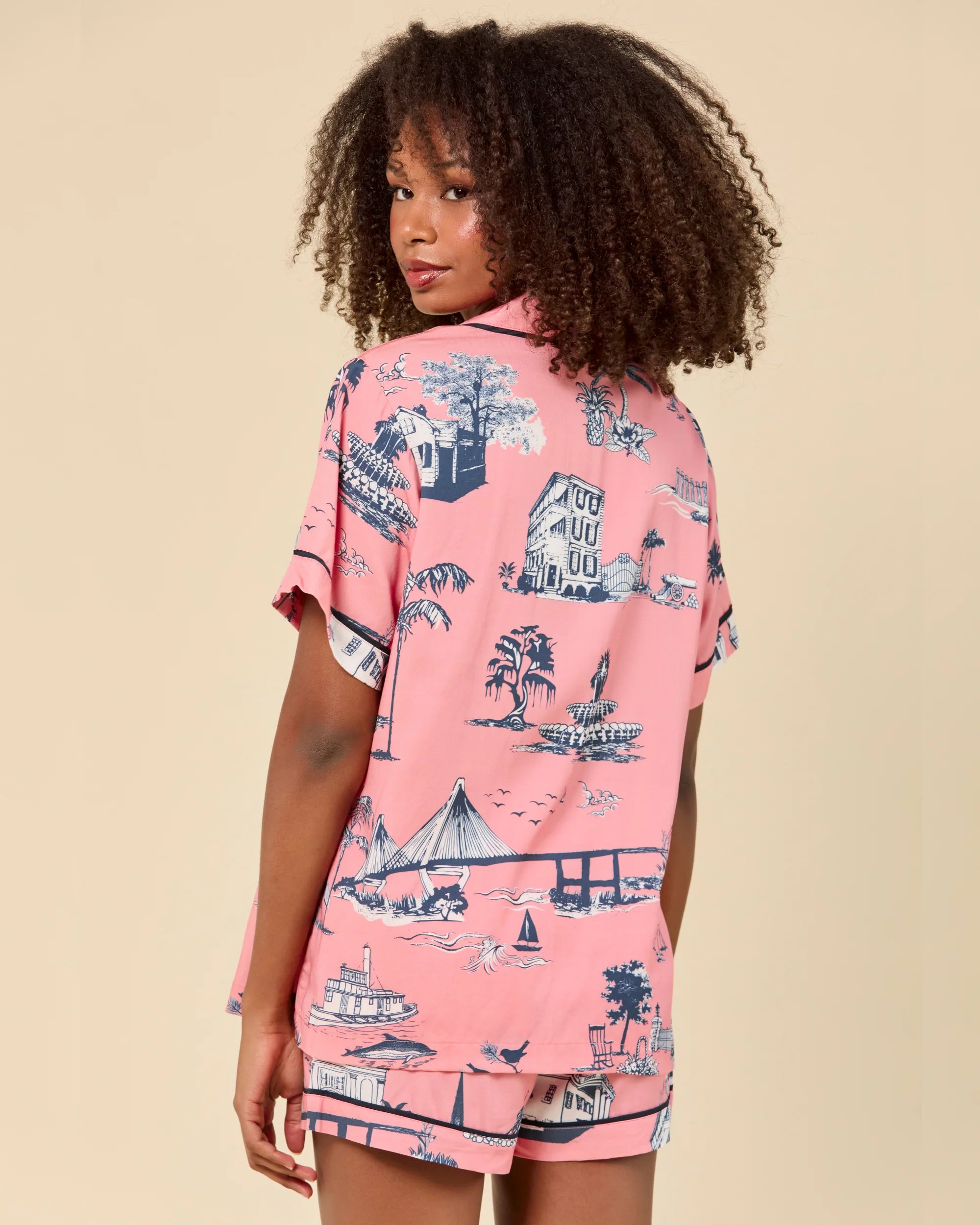 Person wearing a pink shirt with a vintage-style print on a beige background