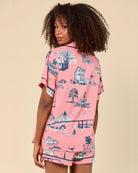 Person wearing a pink shirt with a vintage-style print on a beige background