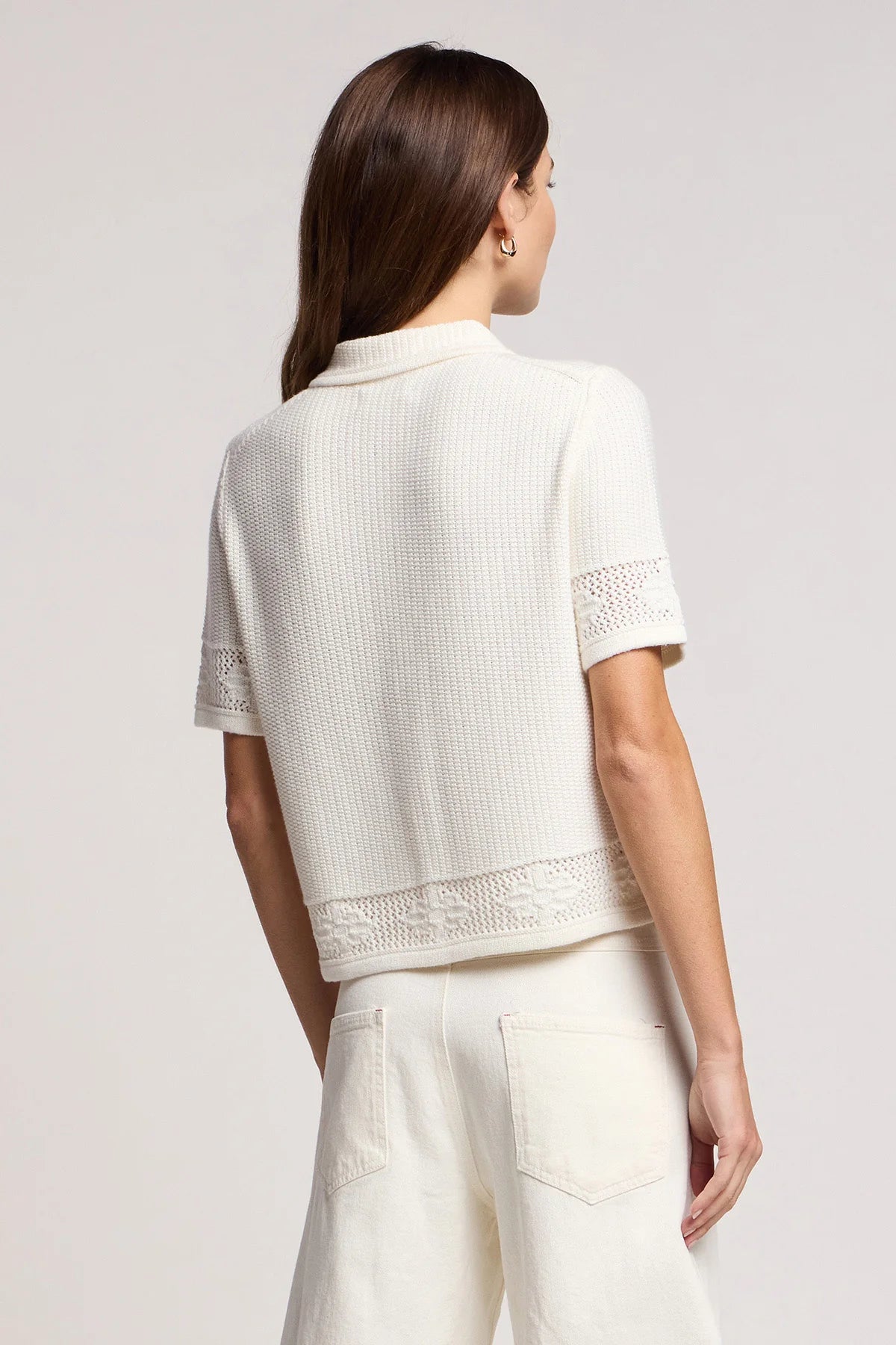 Woman wearing a white textured top and pants on a light gray background