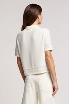Woman wearing a white textured top and pants on a light gray background