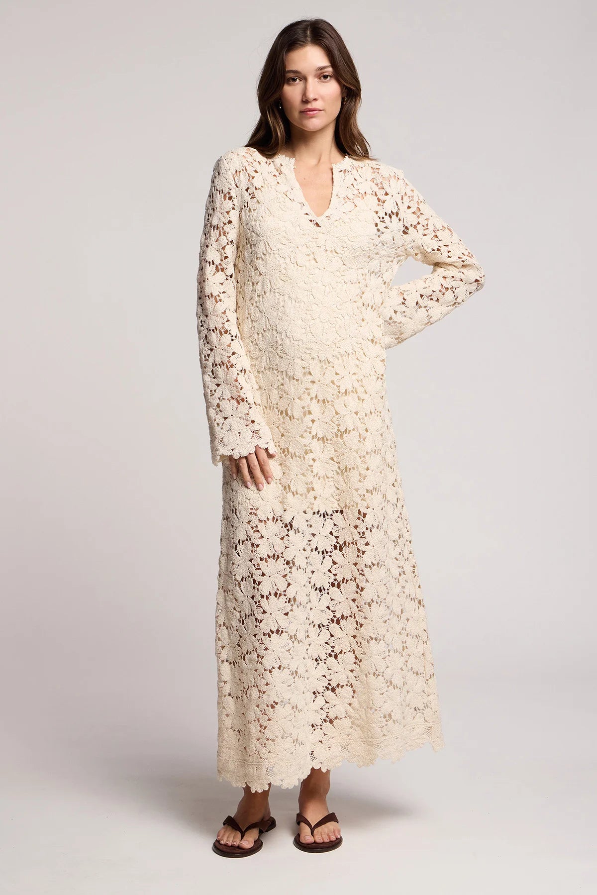 Woman wearing a long beige lace dress on a white background