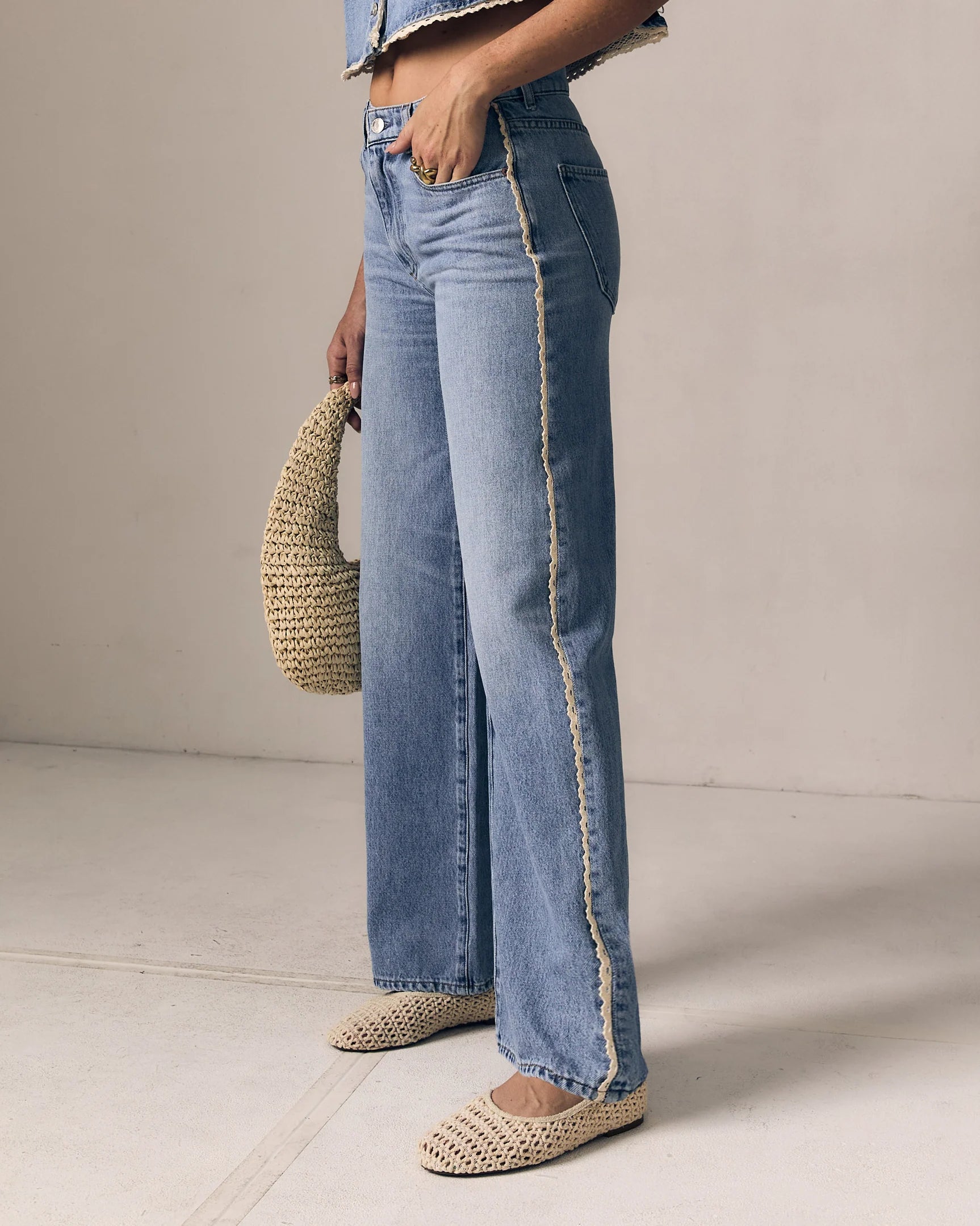Person wearing light blue jeans with a beige background