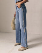 Person wearing light blue jeans with a beige background