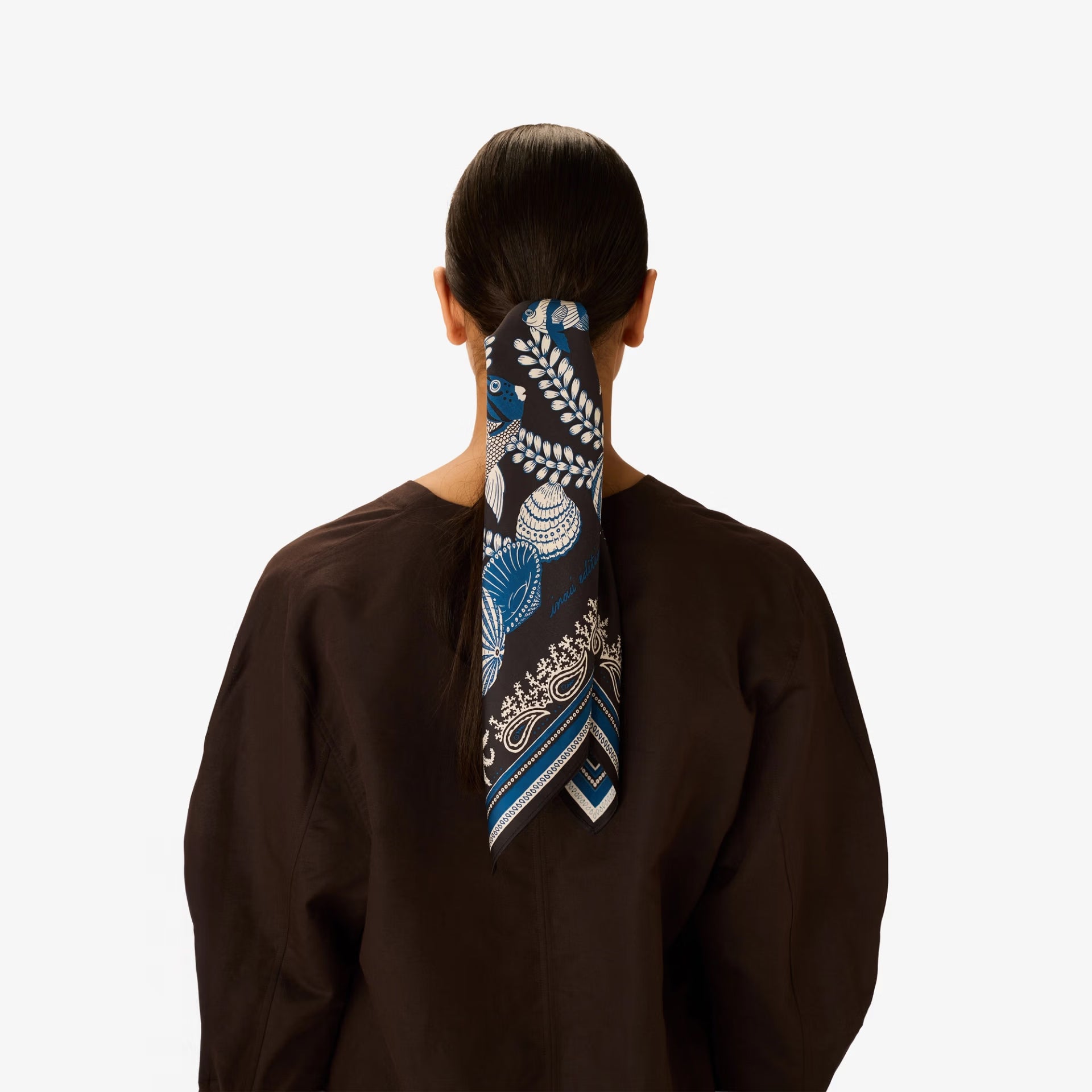 Person wearing a blue and white patterned headscarf on a plain background