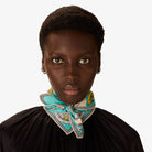 Person wearing a turquoise scarf with a white pattern on a plain background
