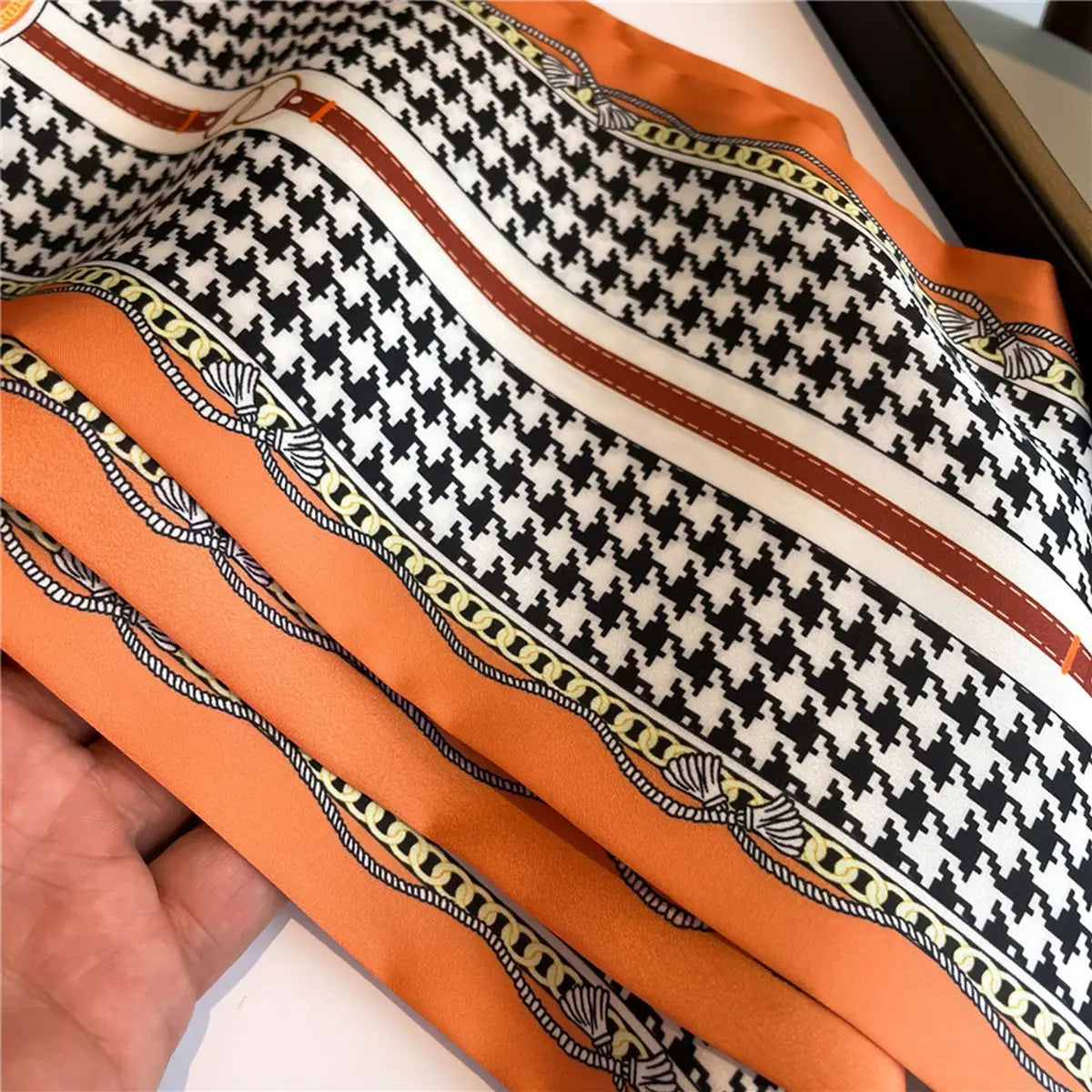 Close-up of a patterned fabric with orange, black, and white design.