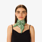 Woman wearing a green patterned scarf around her neck on a white background