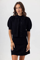 Woman wearing a black outfit with puff sleeves on a white background