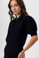 Woman wearing a black short-sleeve dress against a white background