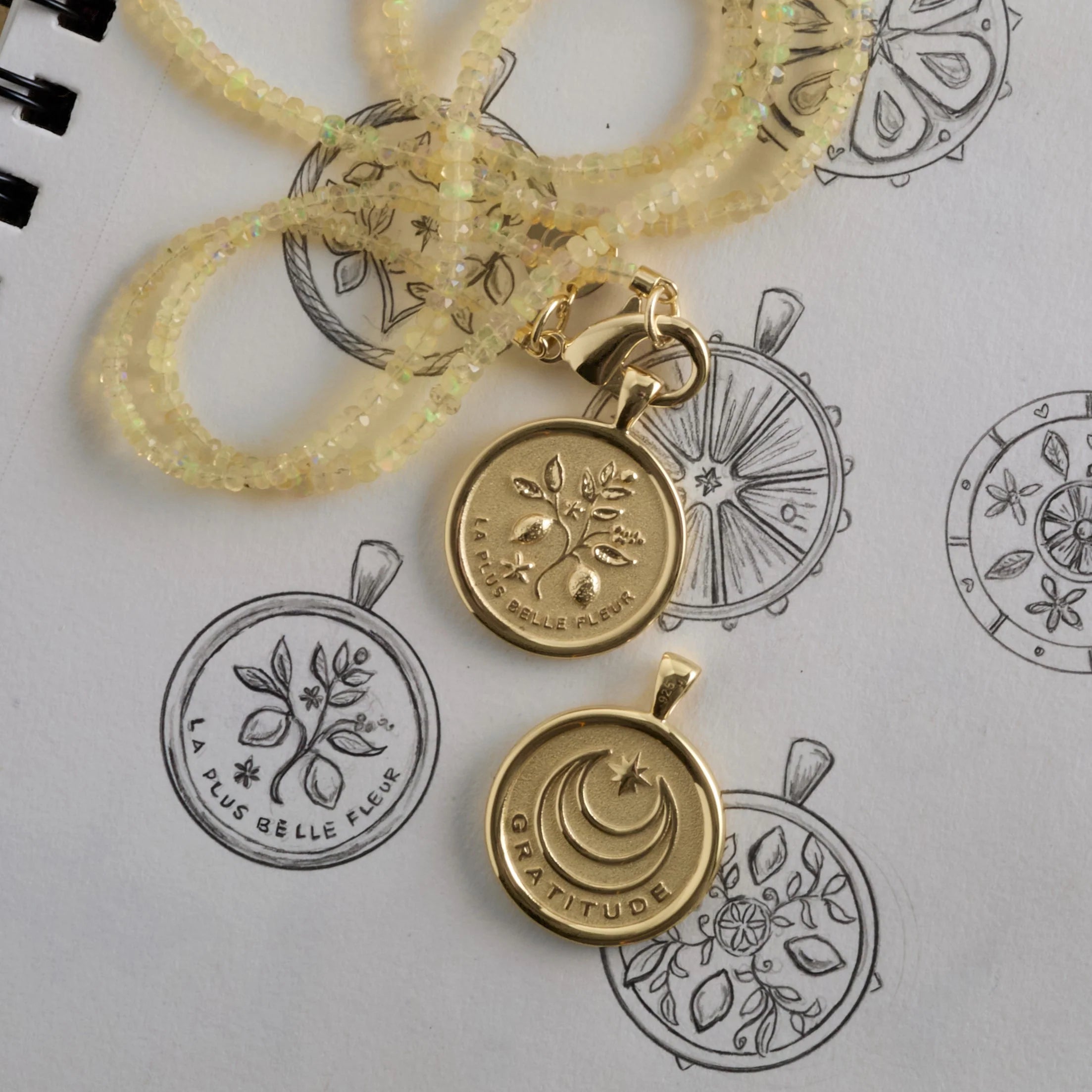 Gold pendants with engraved designs on a white background with black line art.
