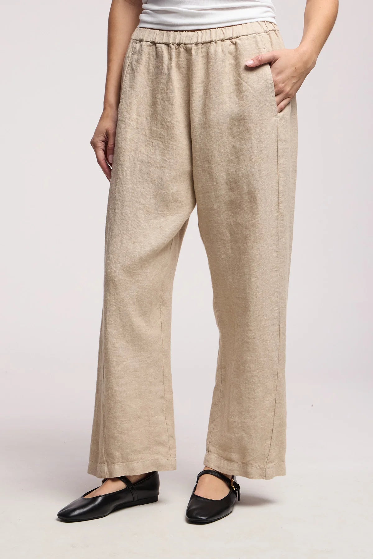 Beige linen pants worn by a person on a white background