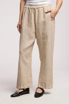 Beige linen pants worn by a person on a white background