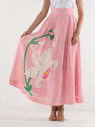 Person wearing a pink skirt with floral design on a white background