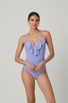 Woman wearing a blue ruffled swimsuit on a plain background