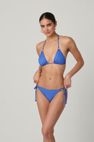 Woman wearing a blue bikini against a gray background
