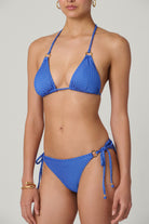 Woman wearing a blue bikini against a gray background