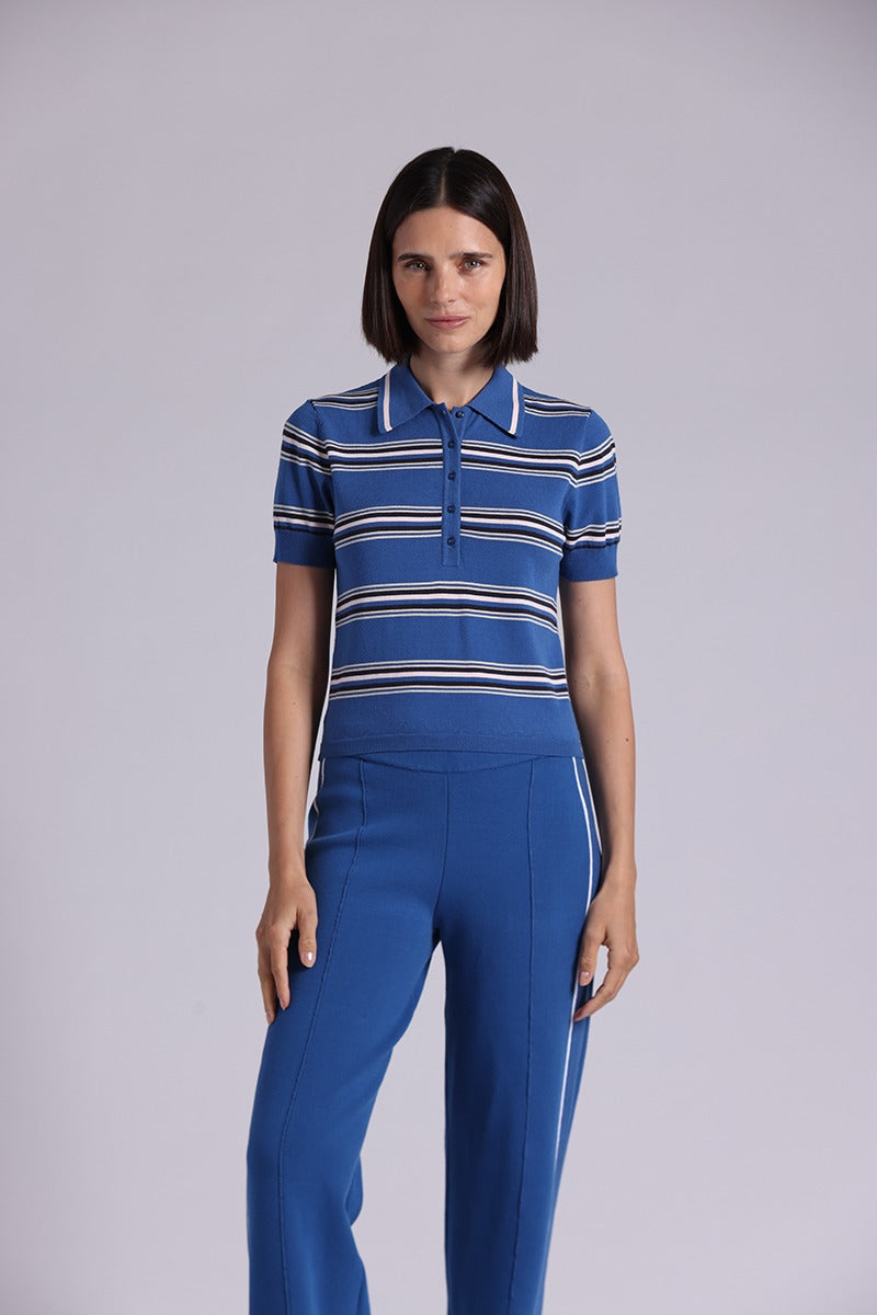 Woman wearing a blue striped polo shirt and matching pants on a light gray background