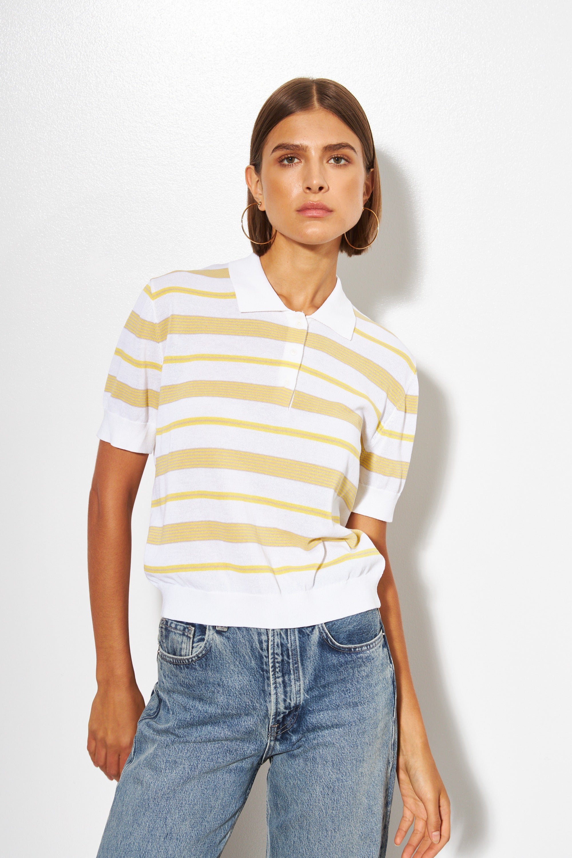 Woman wearing a white and yellow striped shirt with blue jeans on a white background