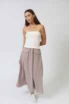 Woman wearing a white strapless top and checkered pants on a white background