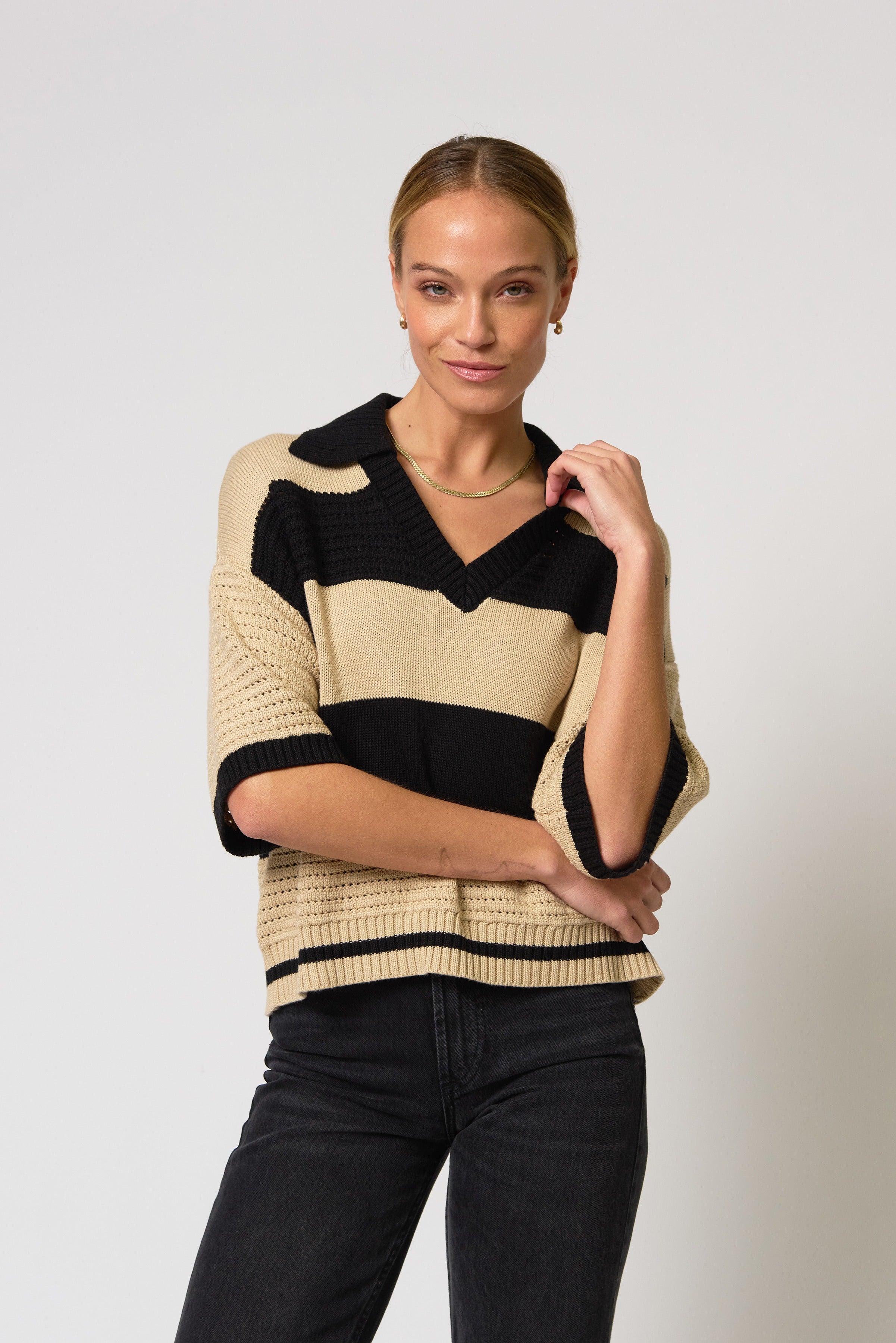 Woman wearing a black and beige striped sweater against a white background
