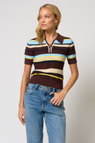 Woman wearing a striped polo shirt and jeans on a plain background