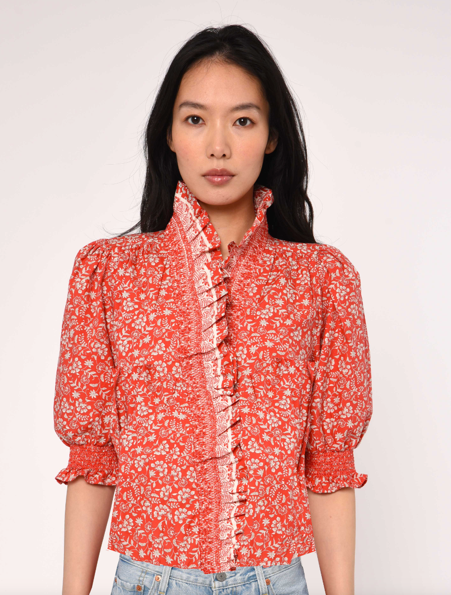 Woman wearing a red floral blouse against a white background