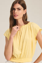 Woman wearing a yellow top against a plain background