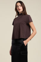 Woman wearing a brown top and black pants against a beige background