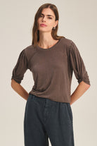 Woman wearing a brown top with balloon sleeves against a beige background