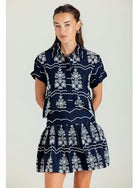 Woman wearing a navy dress with white patterns on a plain background