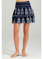Navy blue skirt with white floral pattern worn by a person on a light gray background