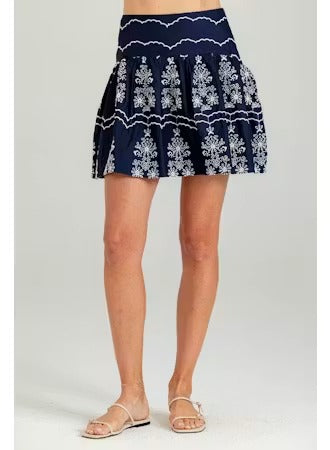 Navy blue skirt with white floral pattern worn by a person on a light gray background