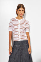 Woman wearing a striped shirt and dark pleated skirt on a white background