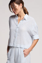 Woman wearing a light blue and white striped shirt and pants on a plain background