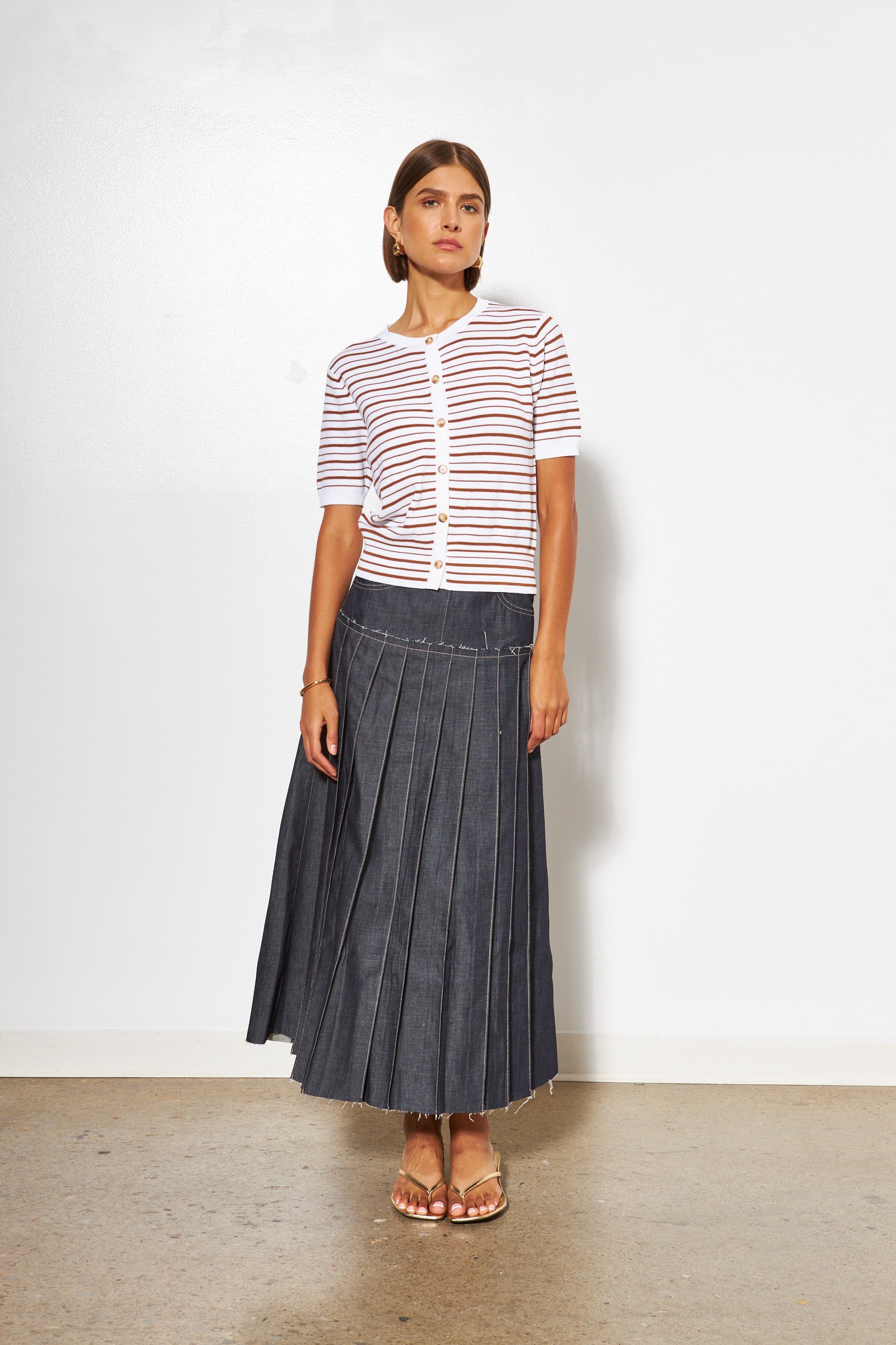 Woman wearing a striped shirt and denim skirt against a white background