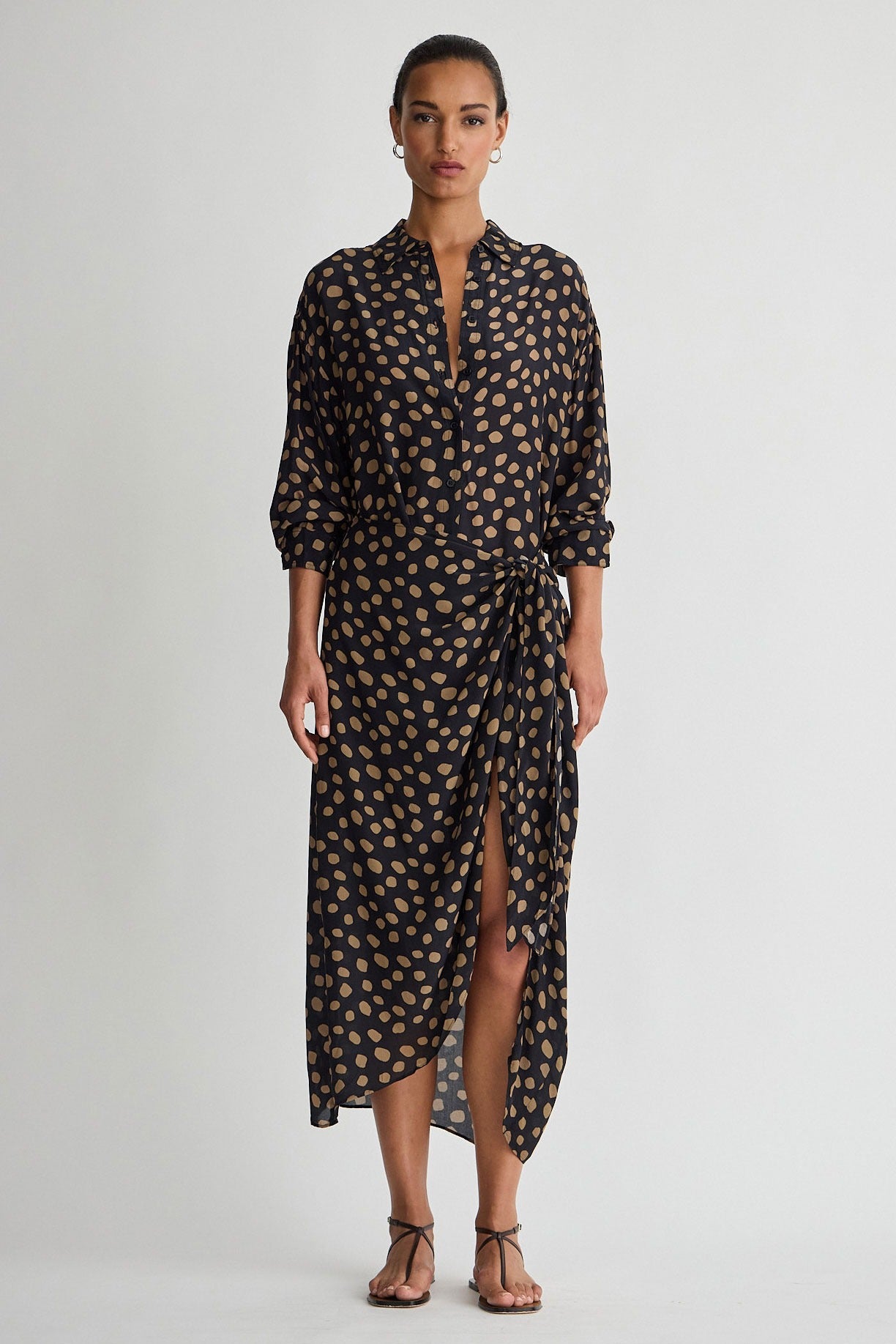 Woman wearing a black and gold patterned dress on a white background