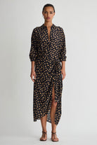 Woman wearing a black and gold patterned dress on a white background